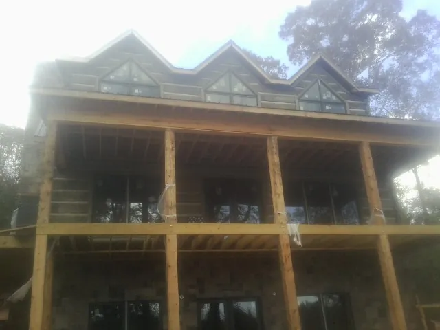 Dormers and porch framing on a large log home under construction — Roof Coating work by our crew in Greenwood