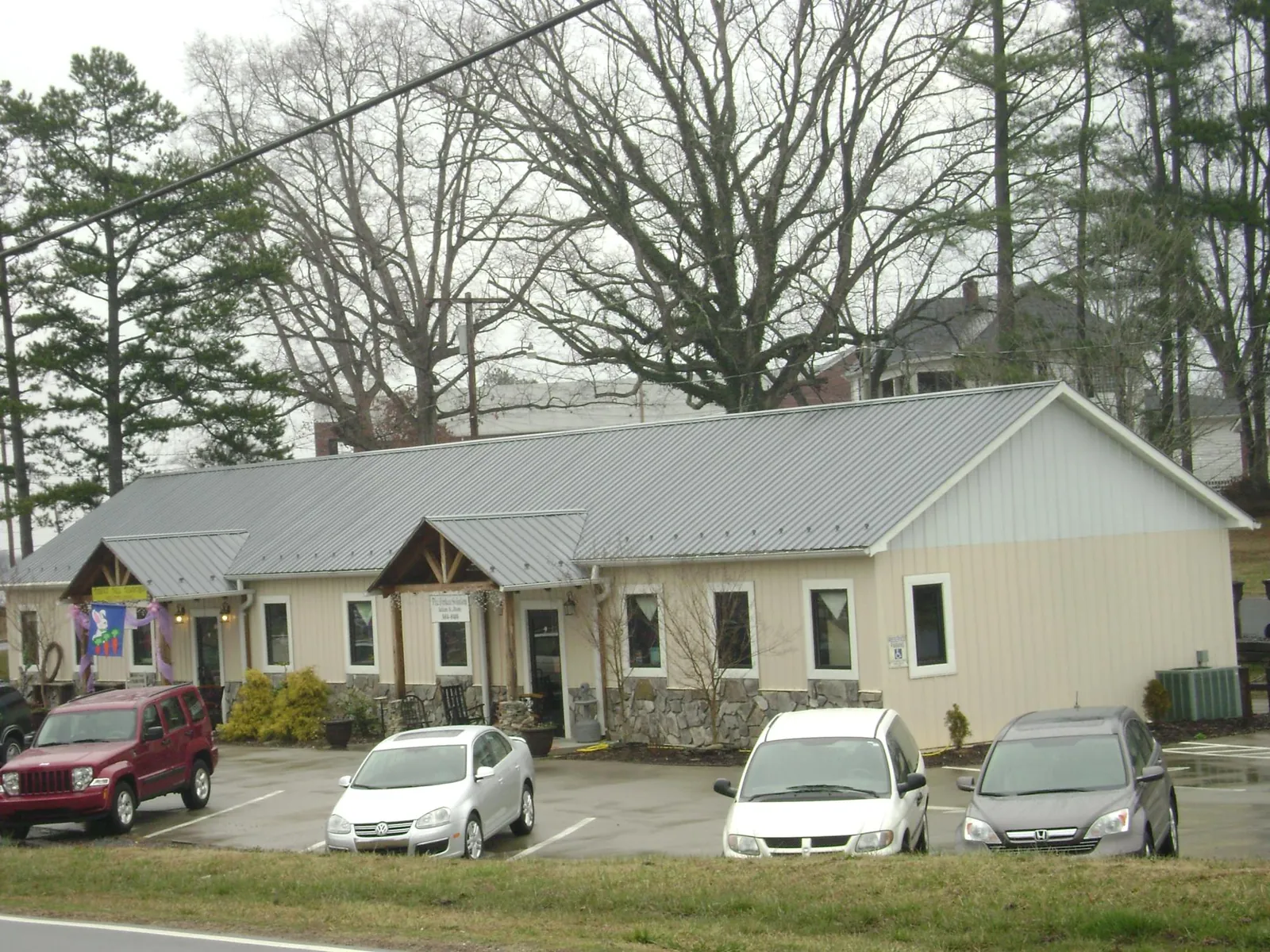Gray metal roof with timber entry brackets on a small commercial building in Greenwood